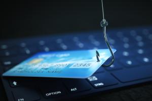 keyboard in background and credit card caught by fishing hook